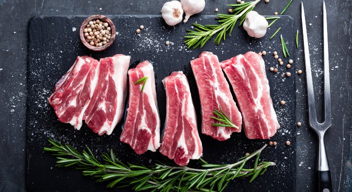 Raw prok chops on a board with rosemary 