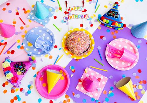 Top-down photo with bright pink and blue party wares for a kid’s birthday party.
