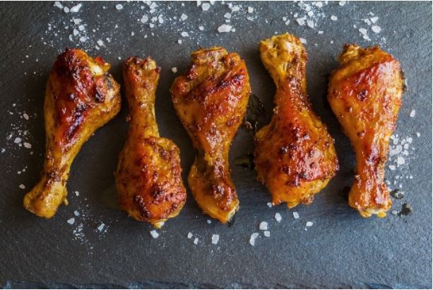 Roast chicken drumsticks with sea salt on a granite countertop.