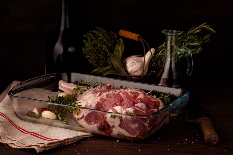 Fresh leg of lamb in a casserole with garlic and rosemary.