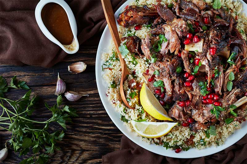 Lamb and couscous salad with wedges of lemon and gravy.