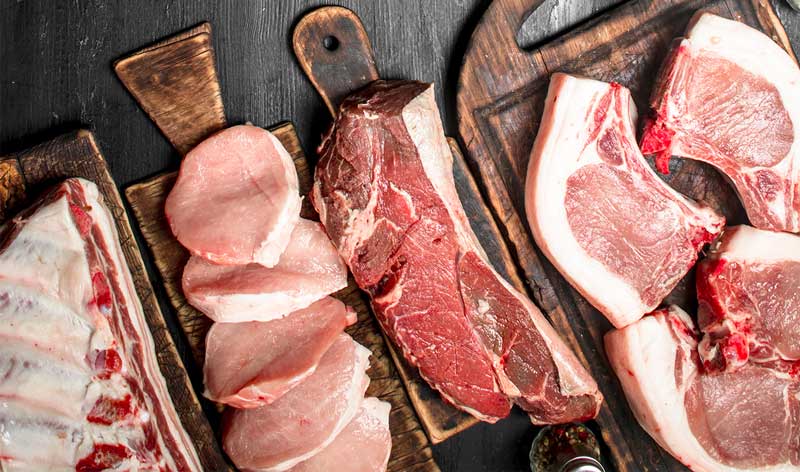 Different cuts of pork arranged on rustic chopping boards.